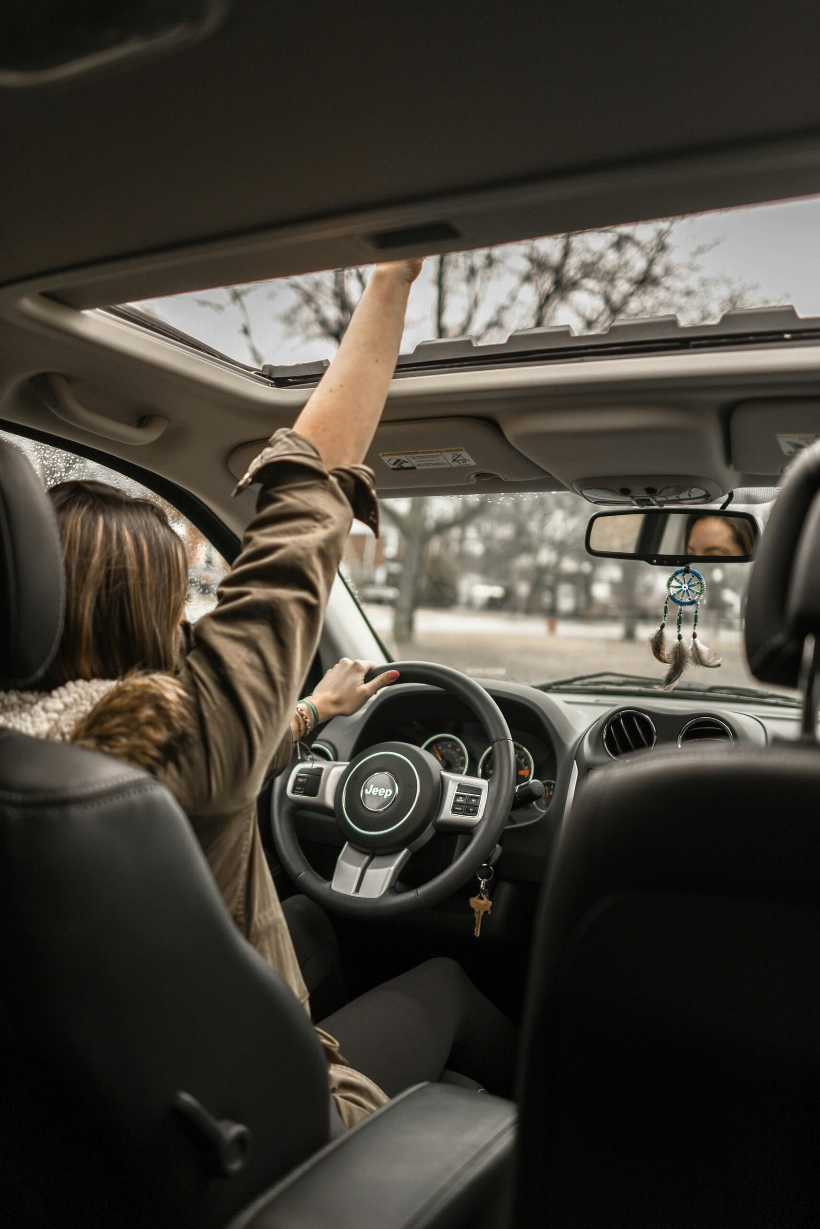 pexels-photo-1051071-1051071 A young woman enjoying a drive with the sunroof open, showing car interior detail.